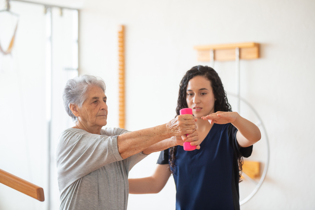 Senior woman lifting weight during physical therapy with occupational therapist